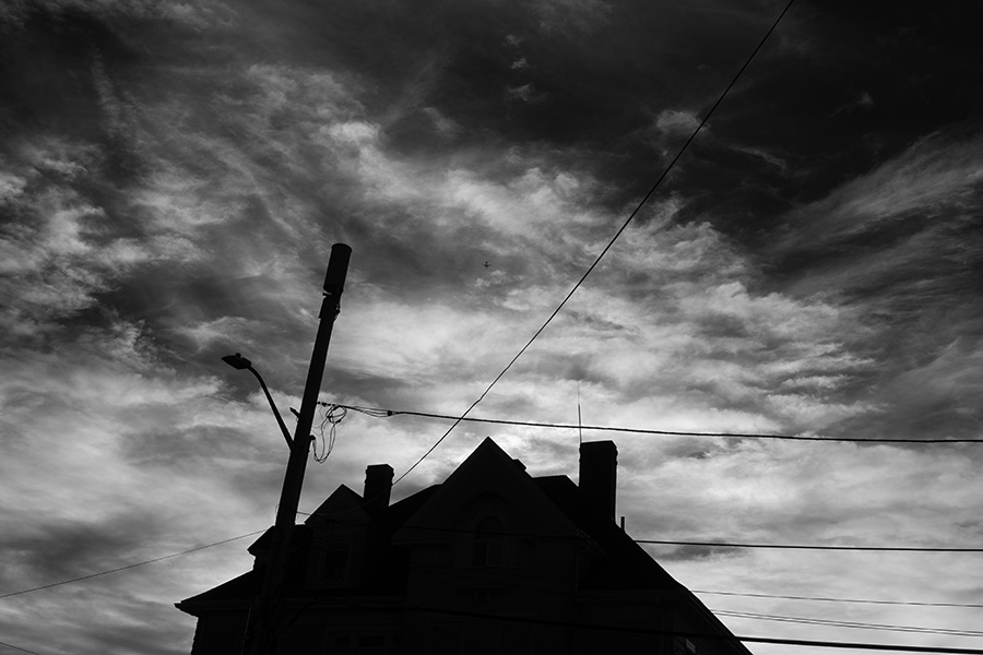 Very Dramatic Infrared Photo of Victorian House in Silhouette Against Moody Sunset Clouds.